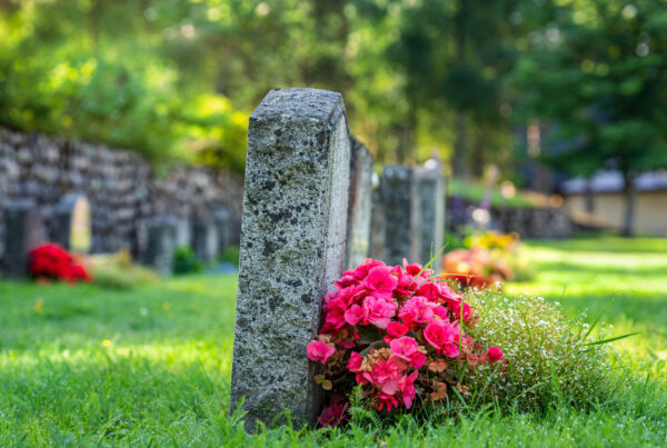 Row of gravestones with colorful flowers on a beautiful and well cared cemetery